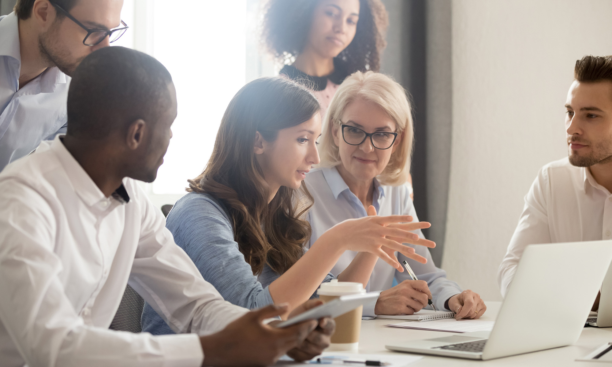 Young female teaching employees in a group with a laptop at an office meeting