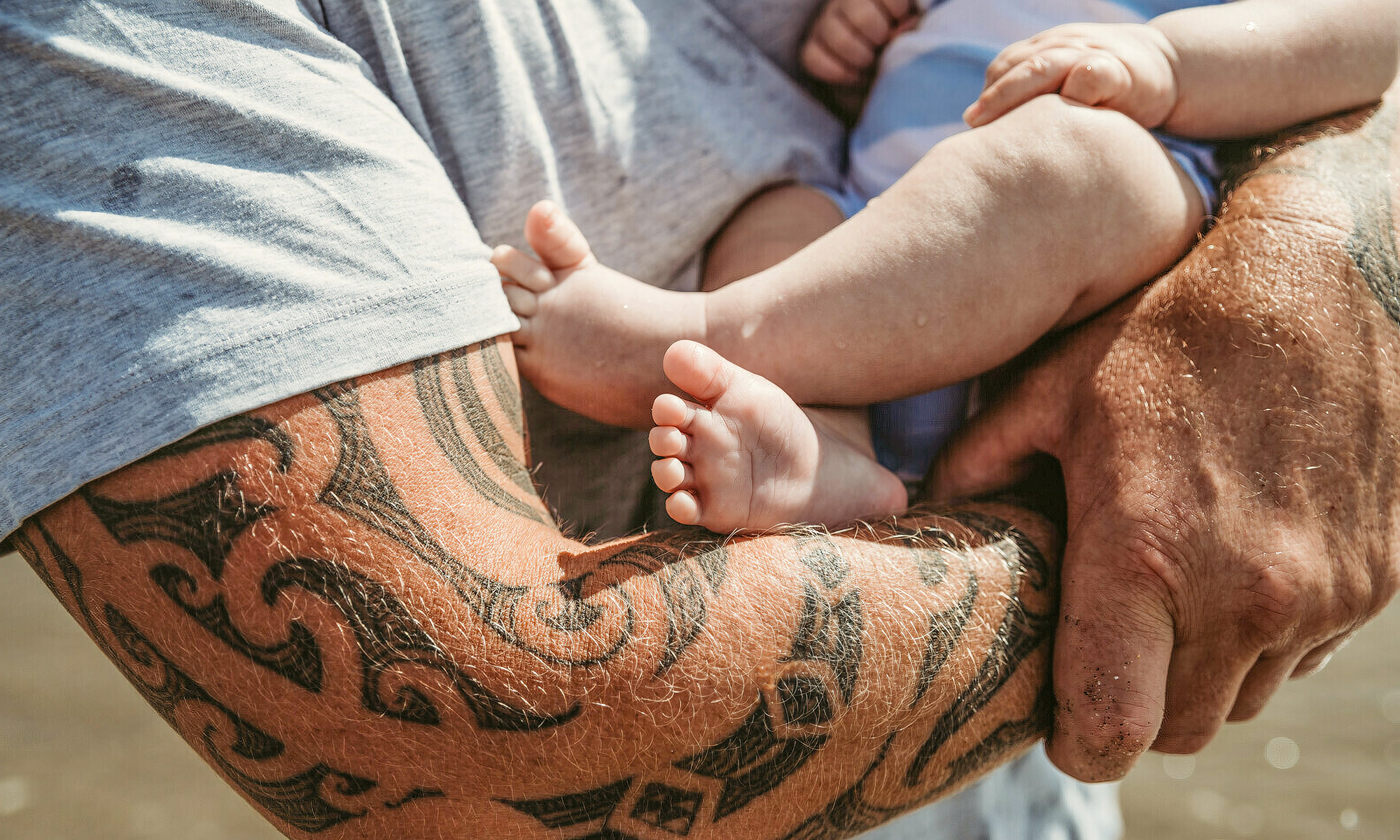 Father with tattoo cradling a baby in his arms